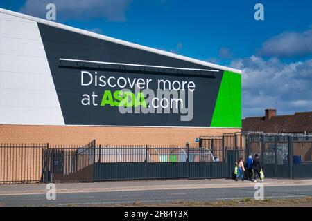 Kunden des Stores passieren Corporate Signage in einem Geschäft der britischen Supermarktkette ASDA, das sich in einem Wohngebiet im Norden Englands befindet. Stockfoto