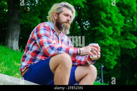 Kaffee zum Mitnehmen. Nachdenklicher Mann mit Kaffee im Freien. Bärtiger Mann mit Papierkaffeebecher. Stockfoto