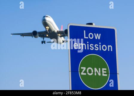 Schild mit emissionsarmer Zone und Landung des Düsenflugzeugs am Flughafen London Heathrow, Großbritannien. Luftverschmutzung. Kohlendioxidemissionen. Luftverkehrsemissionen. Klima Stockfoto