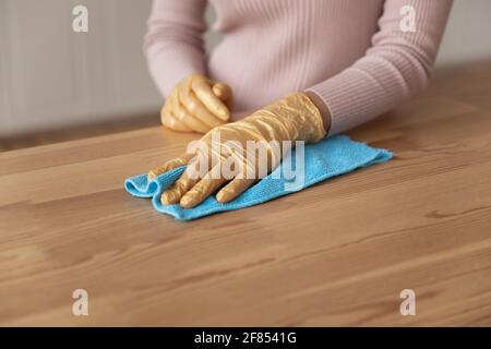 Junge weibliche Hände in Handschuhen mit Lappen, um Möbel zu stauben Stockfoto