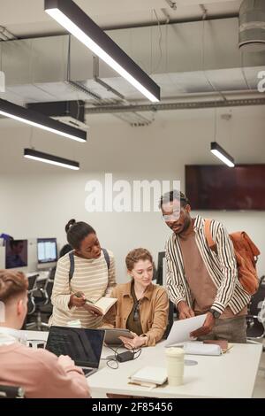 Vertikales Porträt einer Gruppe von Schülern, die in der modernen Schulbibliothek zusammenarbeiten und Computer verwenden, Kopierraum Stockfoto