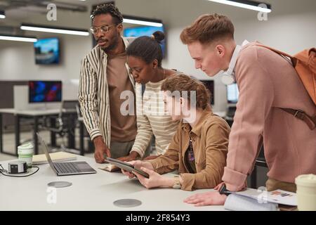 Verschiedene Gruppe von Studenten arbeiten zusammen und verwenden Computer, während Stehen am Tisch im IT-Labor der Schule Stockfoto