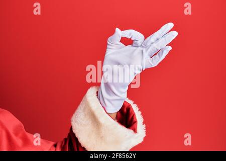 Hand eines Mannes mit weihnachtsmann Kostüm und Handschuhen Auf rotem Hintergrund gestikulierte Genehmigung Ausdruck tut okay Symbol mit Finger Stockfoto