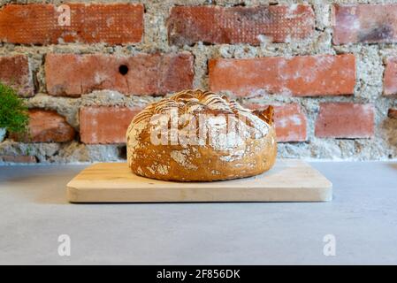Hausgemachtes Sauerteig-Brot, fertig zum Essen vor einer Ziegelwand. Stockfoto