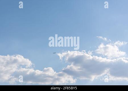 Das Flugzeug am Himmel hebt sich über den weißen, flauschigen Wolken ab. Leichtigkeit, Leichtigkeit, Schwerelosigkeit. Helles Sonnenlicht, natürlicher Sommerhintergrund. Der Nachteil Stockfoto