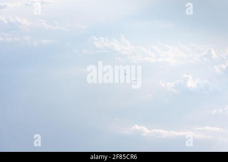 Das Flugzeug ist am Himmel über den weißen Wolken. Leichtigkeit, Leichtigkeit, Schwerelosigkeit. Helles Sonnenlicht, natürlicher Sommerhintergrund. Das Konzept der Trave Stockfoto