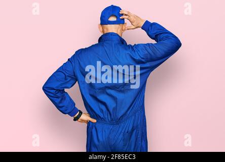 Glatze Mann mit Bart tragen Baumeister Jumpsuit Uniform rückwärts denken Über Zweifel mit Hand auf Kopf Stockfoto