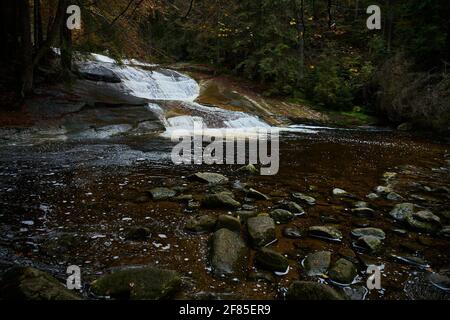 Herbstansicht des Flusses Mumlava und der Wasserfälle in der Nähe von Harrachov Stockfoto