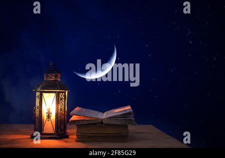 Ornamentale arabische Laterne mit brennender Kerze, die in der Nacht leuchtet. Festliche Grußkarte, Einladung zum muslimischen heiligen Monat Ramadan Kareem. Stockfoto