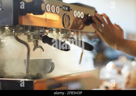 Nahaufnahme einer dampfenden Kaffeemaschine im Café oder Café mit nicht erkennbaren Barista-Druckknöpfen, Kopierbereich Stockfoto