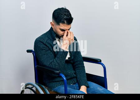 Schöner Mann mit Bart sitzt auf Rollstuhl müde Reiben Nase und Augen Gefühl Müdigkeit und Kopfschmerzen. Stress und Frustration Konzept. Stockfoto