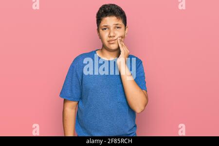 Teenager hispanic Junge trägt Freizeitkleidung berühren den Mund mit der Hand mit schmerzhaften Ausdruck wegen Zahnschmerzen oder Zahnerkrankungen an den Zähnen. Zahnarzt Stockfoto