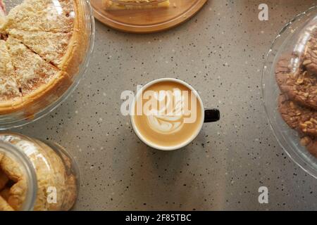Blick von oben auf eine Tasse Kaffee mit Latte-Kunst auf dem Tisch im Café oder in der Bäckerei, Kopierbereich Stockfoto