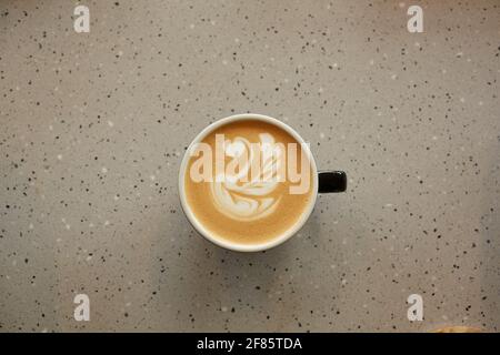 Blick von oben auf eine Tasse Kaffee mit Latte-Kunst auf einem Keramiktisch im Café oder Café, Kopierbereich Stockfoto