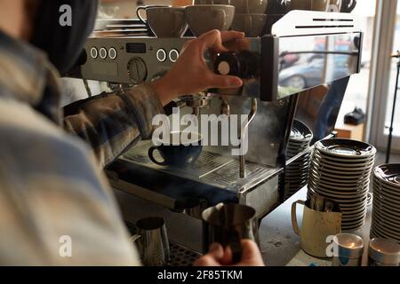 Nahaufnahme eines nicht erkennbaren Barista, der mit einer Kaffeemaschine Kaffee zubereitet, während er an der Bar im Café frischen Kaffee zubereitet, Kopierbereich Stockfoto