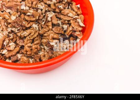 Geschälte Walnüsse in roter Kunststoffplatte auf weißem Hintergrund, isoliert. Stockfoto