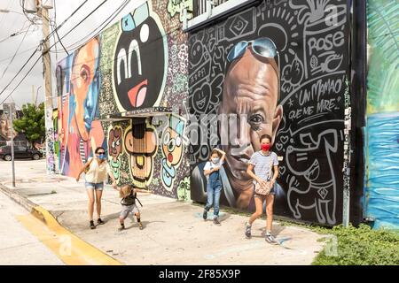 Eine Sightseeing-Familie spaziert durch Wände mit Graffiti-Kunst im Wynwood Art District, Miami, Florida, USA Stockfoto