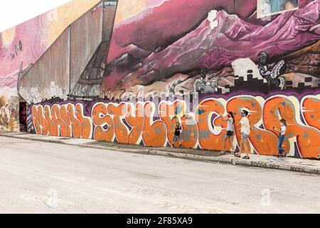 Eine Sightseeing-Familie geht im Wynwood Art District, Miami, Florida, USA, an einer mit Graffiti-Kunst bedeckten Wand vorbei Stockfoto