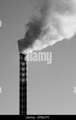 Eine vertikale Graustufenaufnahme von Rauch aus einer Fabrik Stockfoto
