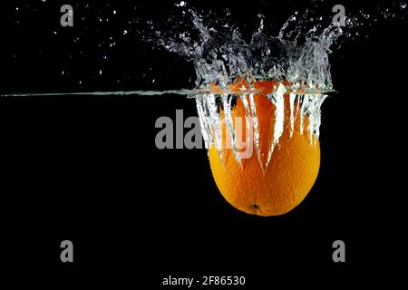 Mandarin fällt auf schwarzem Grund ins Wasser Stockfoto