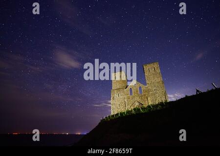 Reculver, Kent, Großbritannien. 12. April 2021: Wetter in Großbritannien. Am 11./12. April wurde in der ruinierten Kirche von Reculver, die Anfang des 19. Jahrhunderts aufgrund der Erosion des Meeres verlassen wurde, ein klarer Himmel mit Sternen und einigen Wolken, der als Navigationshilfe für Schiffe gerettet wurde. Windparks und Schiffe sind am Horizont zu sehen. Kredit: Alan Payton/Alamy Live Nachrichten Stockfoto