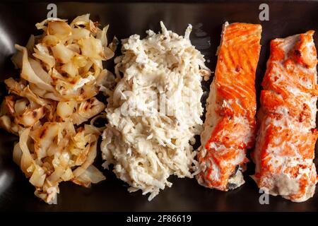 Eine Portion im Ofen gekochter marinierter Lachsfilets mit Kohl und Sellerie-Salaten, um den Ballaststoff- und Vitamingehalt zu erhöhen. Eine gesunde, ausgewogene Ernährung concep Stockfoto