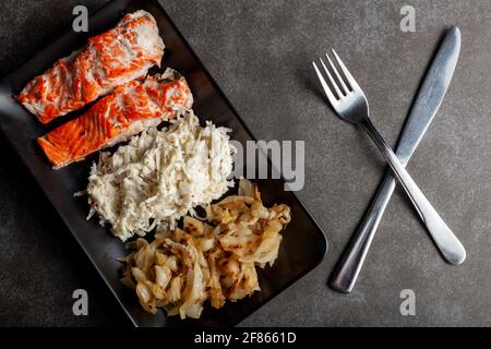 Eine Portion im Ofen gekochter marinierter Lachsfilets mit Kohl und Sellerie-Salaten, um den Ballaststoff- und Vitamingehalt zu erhöhen. Eine gesunde, ausgewogene Ernährung concep Stockfoto