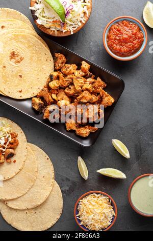 Nahaufnahme eines mexikanischen Taco-Tellers mit Maistortillas, vorgekochten Hühnerstücken, Kohlschlaw, geschreddertem Käse, Salsa und Rahmsoße Stockfoto