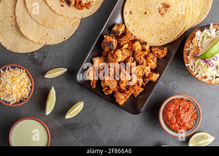 Nahaufnahme eines mexikanischen Taco-Tellers mit Maistortillas, vorgekochten Hühnerstücken, Kohlschlaw, geschreddertem Käse, Salsa und Rahmsoße Stockfoto