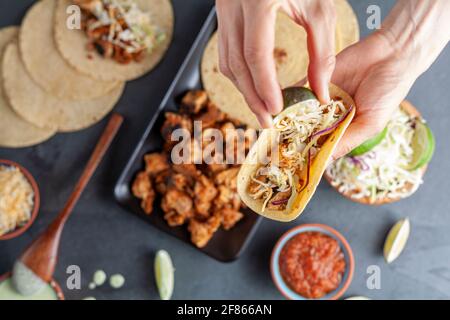 Nahaufnahme eines mexikanischen Taco-Tellers mit Maistortillas, vorgekochten Hühnerstücken, Kohlschlaw, geschreddertem Käse, Salsa und Rahmsoße Stockfoto