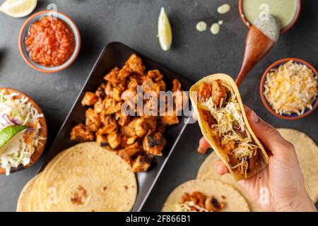 Nahaufnahme eines mexikanischen Taco-Tellers mit Maistortillas, vorgekochten Hühnerstücken, Kohlschlaw, geschreddertem Käse, Salsa und Rahmsoße Stockfoto