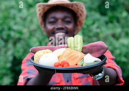 Afrikanischer Landwirt, der ein Gemüsepaket hält. Bio-Gemüse bereit, um in Salat Lieferservice zu dienen Stockfoto