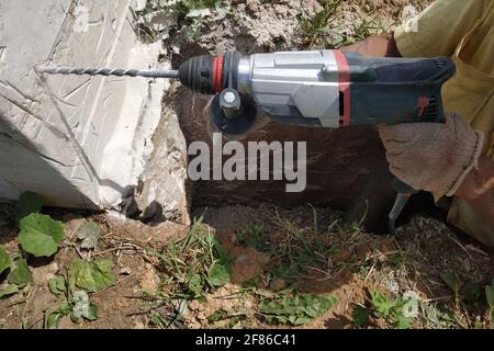 Bohren eines Lochs in die Betonwand mit einem Presshammer, Perforator in Betrieb.neu Stockfoto