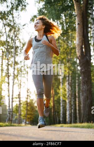 Voller wuchs einer jungen schlanken Frau, die im Morgenwald läuft. Stockfoto