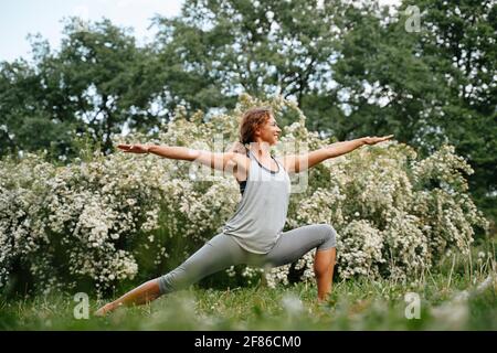 Junge sportliche Frau praktiziert Yoga im Park Stockfoto