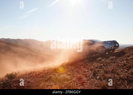 Ein 4x4 hinterlässt eine Spur von Staub in der Sonne, während es eine Berg Schotterpiste klettert. Stockfoto