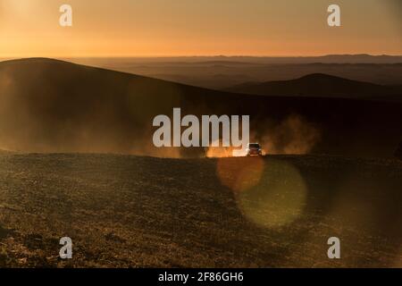 Ein 4x4 hinterlässt eine Spur von Staub in der Sonne, während es eine Berg Schotterpiste klettert. Stockfoto