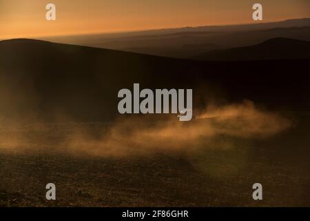 Ein 4x4 hinterlässt eine Spur von Staub in der Sonne, während es eine Berg Schotterpiste klettert. Stockfoto