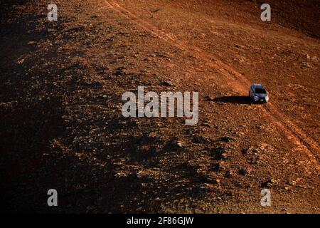 Ein 4x4 hinterlässt eine Spur von Staub in der Sonne, während es eine Berg Schotterpiste klettert. Stockfoto