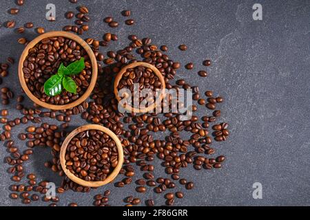 Geröstete braune Kaffeebohnen auf grauem Hintergrund. Kaffeebohnen in Holzschüsseln. Draufsicht. Stockfoto