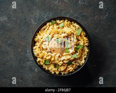 Pakistanische Küche - Biryani-Reis mit Huhn und Raita-Joghurt-Dip. Köstliche hyberabadi Huhn Biryanion schwarz strukturierten Hintergrund. Ansicht von oben oder flach liegend Stockfoto