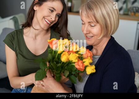 Tochter, die einer liebevollen Mutter einen Blumenstrauß schenkt Stockfoto