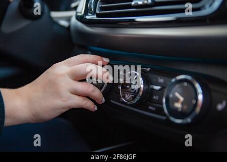 Die Hand der Frau schaltet die Klimaanlage im Auto. Fahrer einschalten Auto Klimaanlage. Reisen mit dem Auto. Kein Gesicht Stockfoto