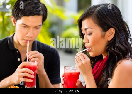 Asiatischer Mann und Frau im Restaurant trinken Cocktails Stockfoto