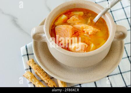 Hausgemachte Suppe mit Lachs mit Brotscheiben auf Marmorboden Stockfoto