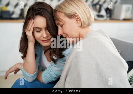 Mutter und Erwachsene Tochter in einer tröstenden Umarmung Stockfoto