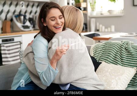 Ältere Frau gratuliert ihrer Tochter zum positiven Schwangerschaftstest Stockfoto