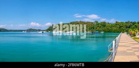 Panoramablick auf die schöne Muelle Bay im Ferienort Puerto Galera, Philippinen, mit Freizeitjachten, die in ruhigem türkisfarbenem Wasser vertäut sind. Stockfoto