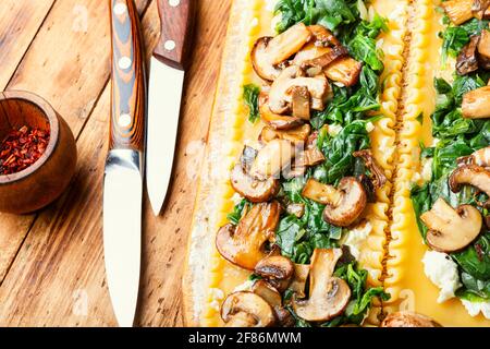 Lasagne mit Pilzen, Käse und Spinat auf Holztisch.traditionelle italienische Küche. Stockfoto