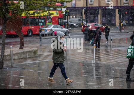 London, Großbritannien. 12 2021. April: Pendler machen sich auf den Weg durch einen überraschenden Schneesturm im Frühling in Wimbledon am ersten Tag werden die Einschränkungen des Coronavirus in England aufgehoben, damit die Menschen ihre Frisur machen und außerhalb von Pubs und Restaurants essen und trinken können. 12. April 2021 Wimbledon, England. Kredit: Jeff Gilbert/Alamy Live Nachrichten Stockfoto